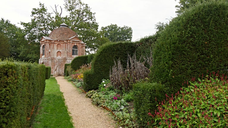 A domed red brick building sits at the end of a formal garden path.